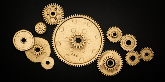 Projektmanagement Anordnung goldener Zahnräder in verschiedenen Größen auf schwarzem Grund
